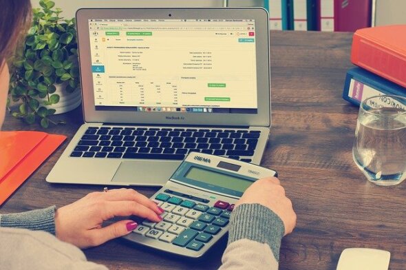 mulher frete a computador, com calculadora nas mãos