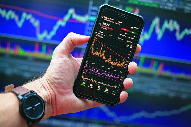Mão segura um celular com um gráfico de ações
