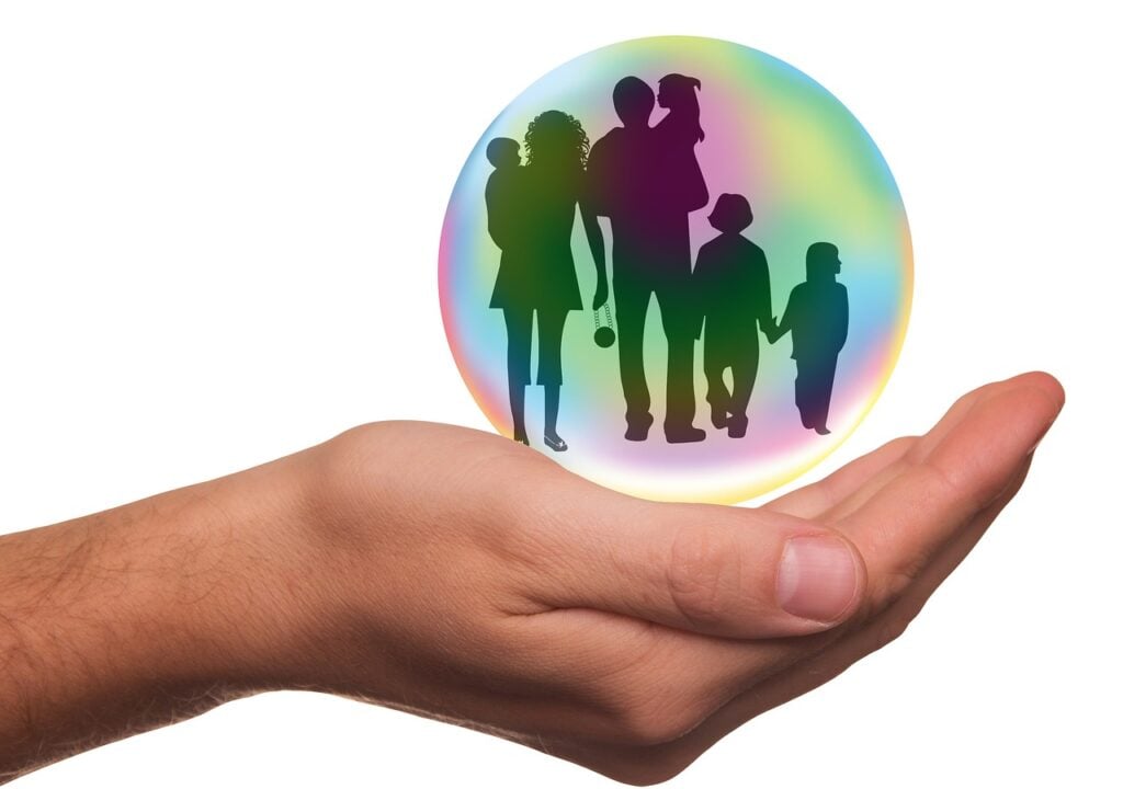 Mãos protegendo uma família: conheça o seguro de vida vitalício e seguro de vida temporário