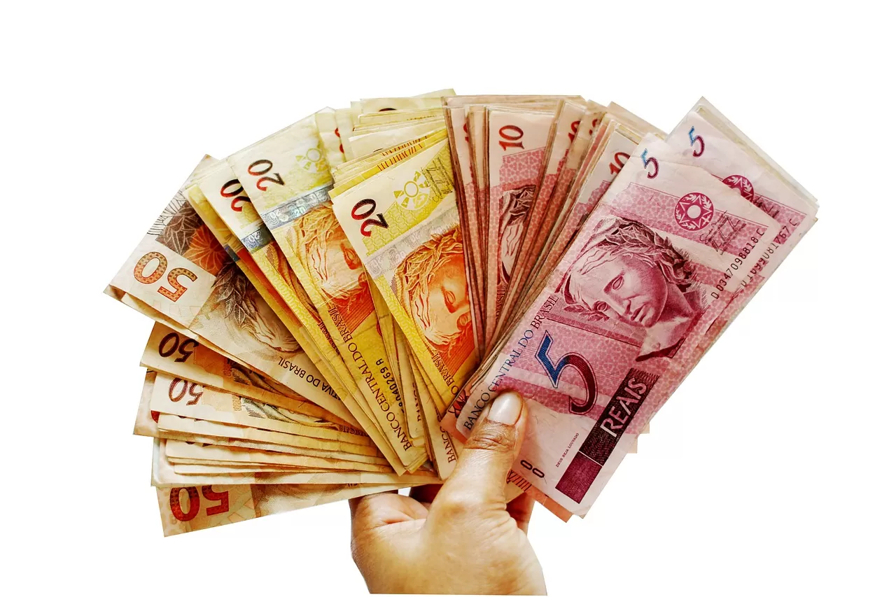 Foto mostra pessoa segurando cédulas de reais em formato de leque para ilustrar valores a receber do Banco Central
