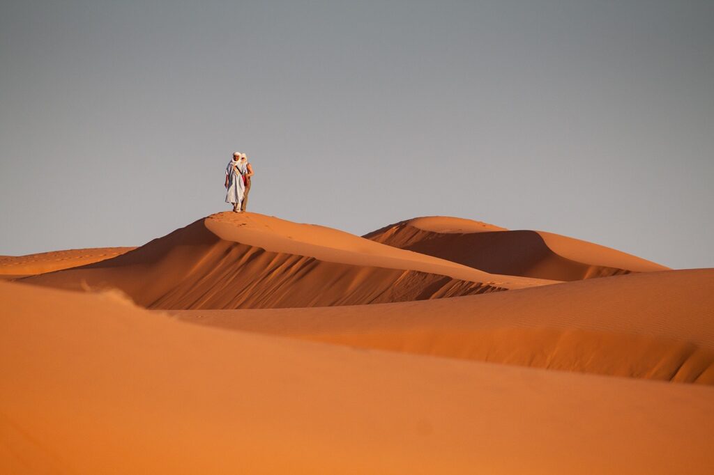 Imagem mostra um beduíno andando no deserto.