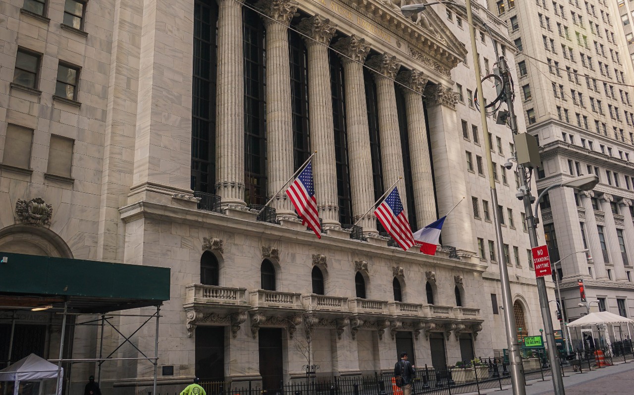 Fachada da Bolsa de Nova York (NYSE). Prédio com clunas gregas e bandeiras norte-americanas na fachada. Saiba como investir na NYSE. Ações nos EUA: melhores e piores