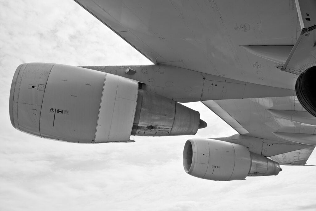 Imagem mostra um avião em voo, sendo a parte da turbina.