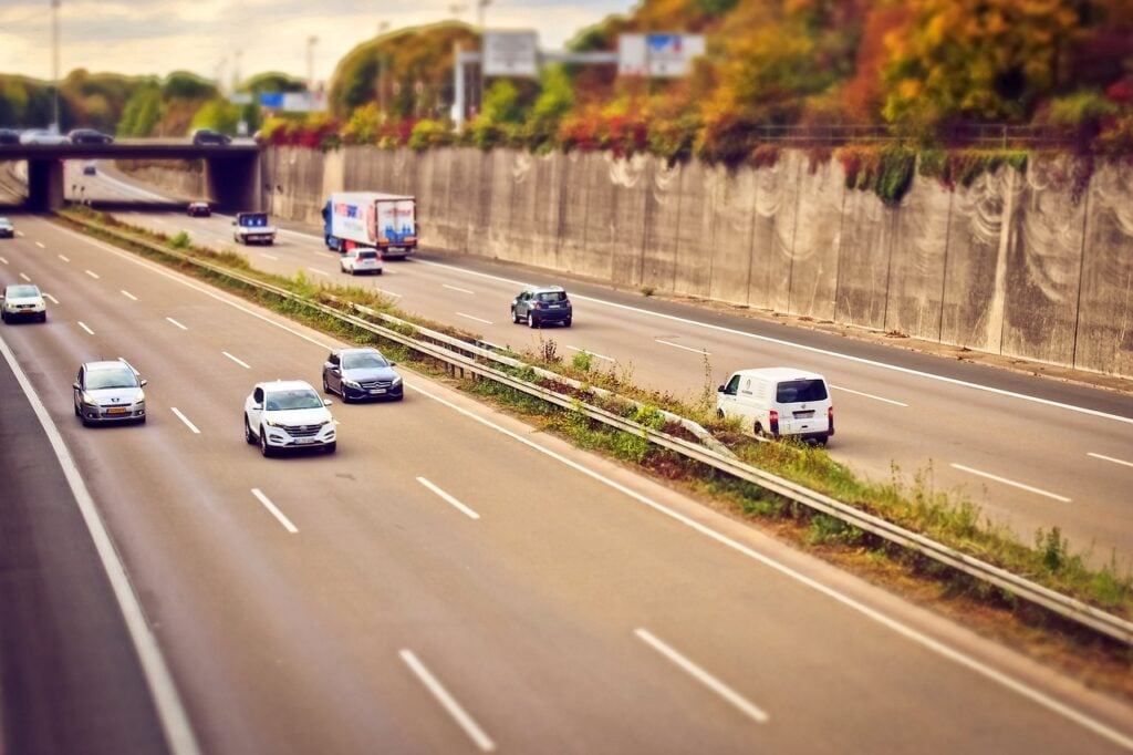 A imagem mostra uma avenida movimentada de carros.