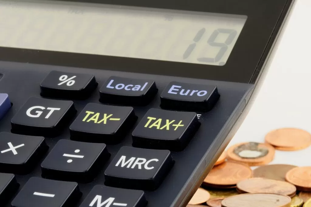 Imagem mostra uma calculadora e algumas moedas.