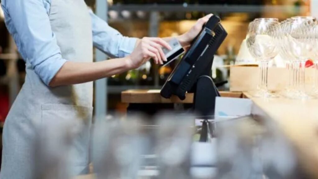 Caixa de supermercado passando um cartão na máquina