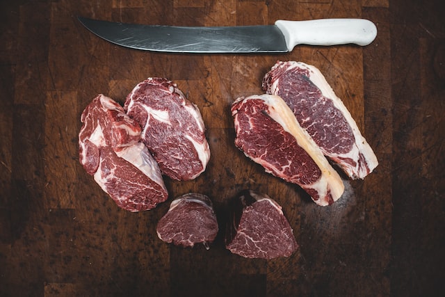 Imagem mostra uma bandeja de carne para corte e uma faca.