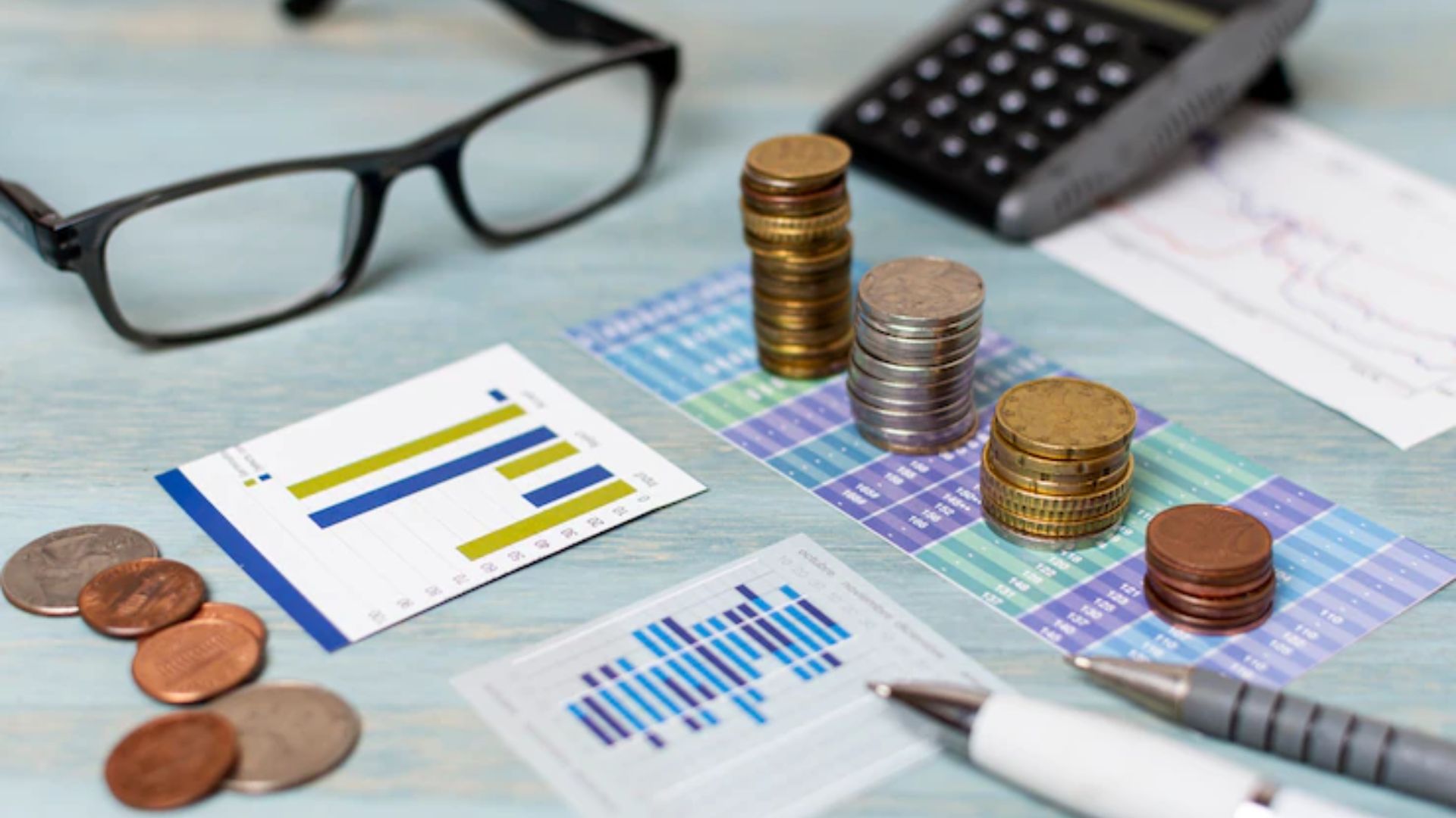 Objetos para planejamento financeiro com calculadora, planilhas, óculos, moedas, dentre outros