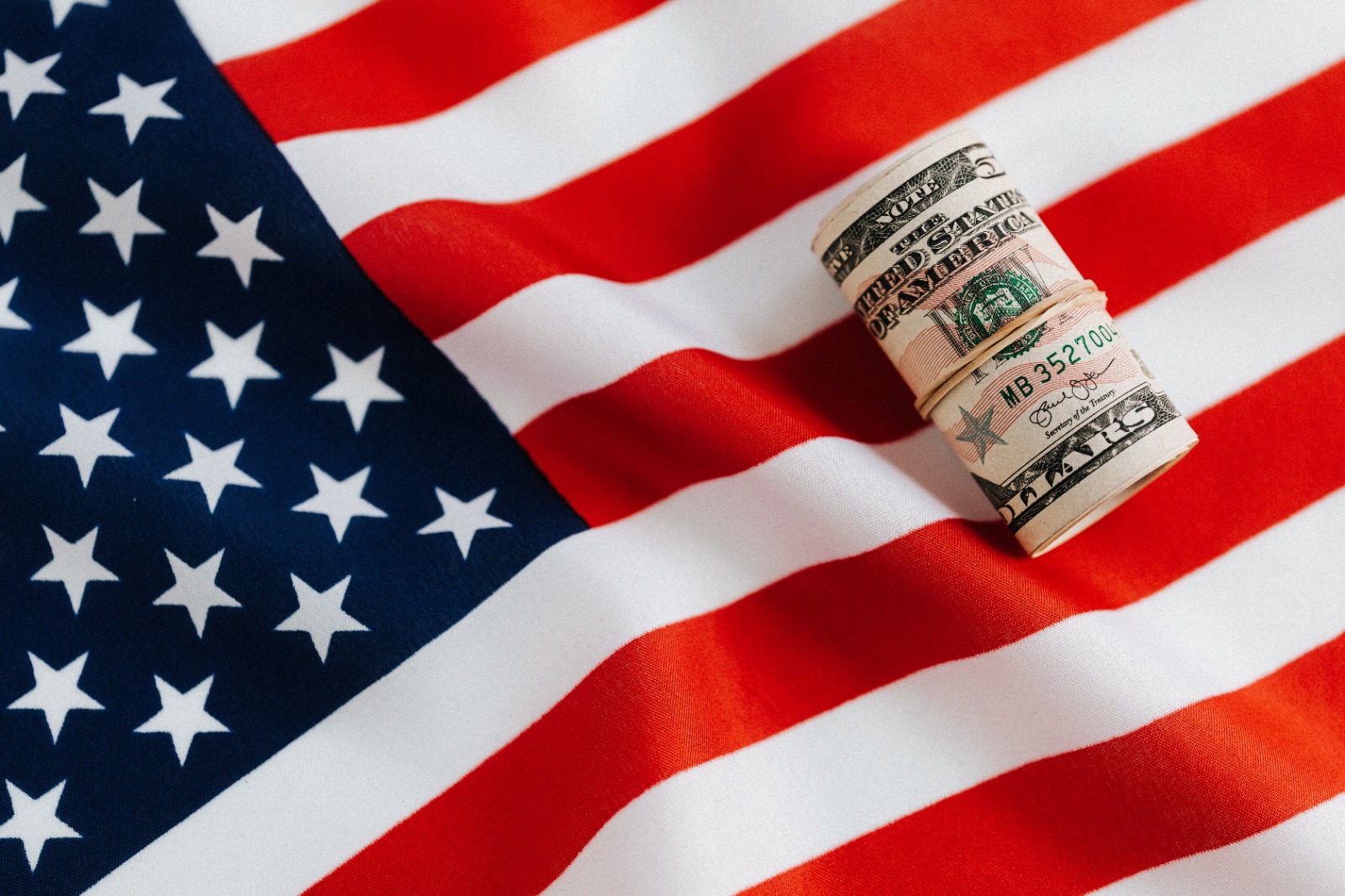 Invista no Exterior e tenha patrimônio em dólar: bandeira dos EUA com nota de dólar/