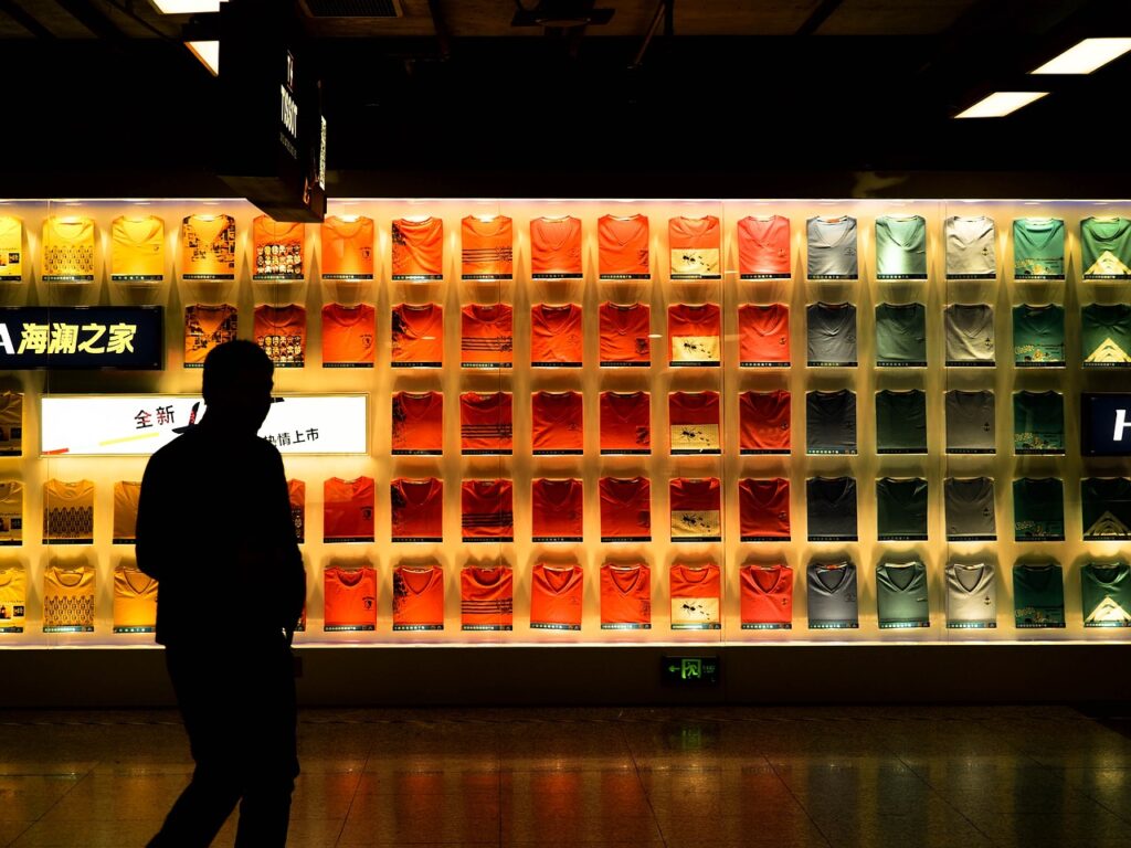 Imagem mostra um homem olhando camisetas em uma vitrine dentro do metrô de Xangai, na China.
