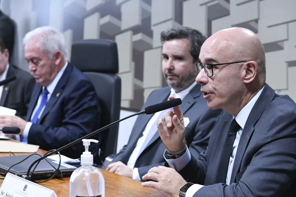 Sérgio Rial, uma pessoa sem cabelos e de óculos, falando ao microfone sobre o Caso Americanas (AMER3)