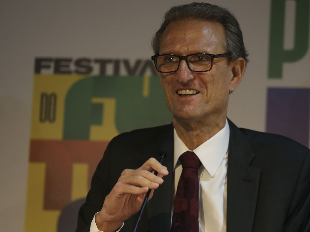 Maurício Tolmasquim, um homem alto e magro, com terno escuro e de óculos sorri em uma entrevista coletiva