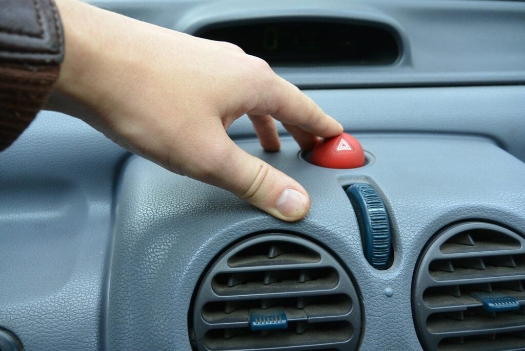 Imagem mostra uma mão sobre um painel de carro popular.