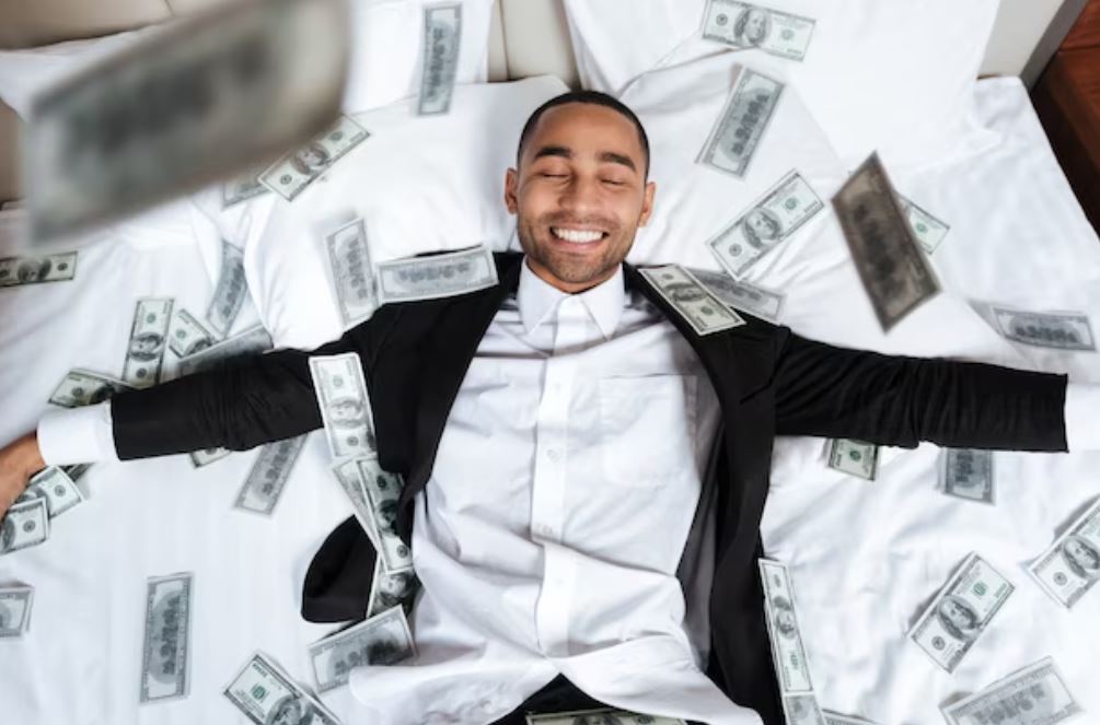 foto de homem deitado em cama, com notas de dólares voando: juntar R$ 1 milhão e se aposentar