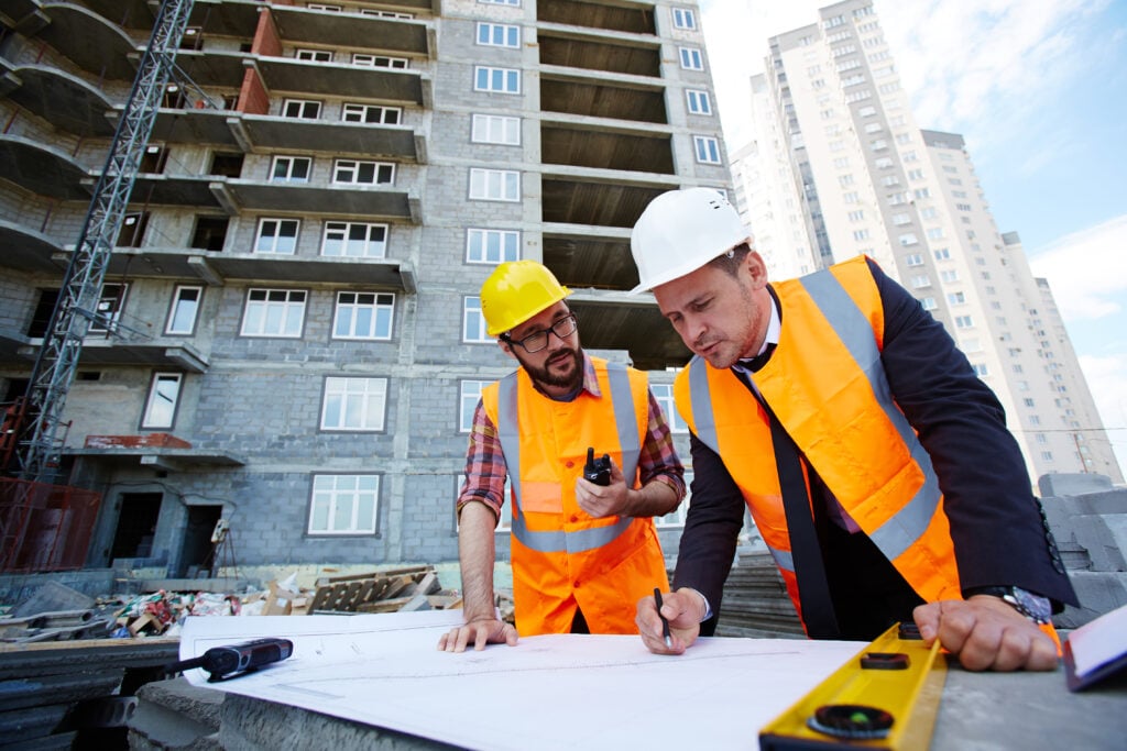 Trabalhadores da construção civil estudando planta de um empreendimento.
Fonte: Freepik