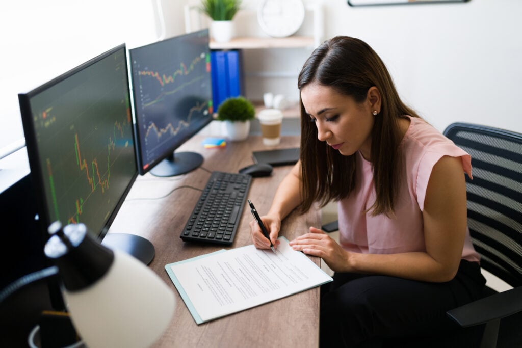 Mulher estudando com gráficos de investimentos no computador