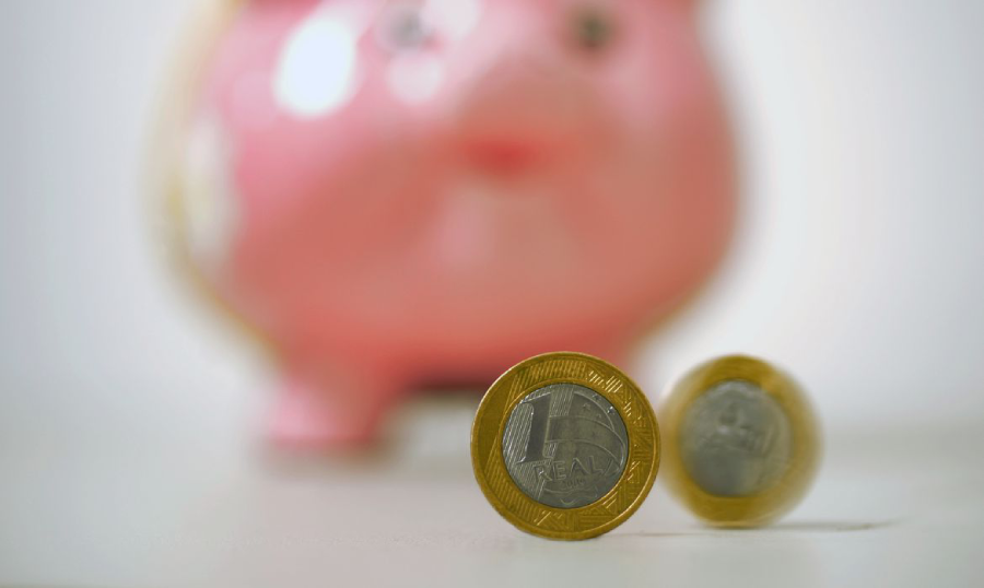 Poupança: imagem mostra cofrinho e duas moedas de R$ 1