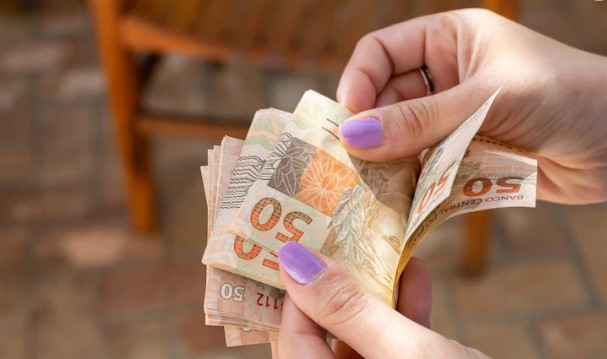 foto de mulher contando notas de 50 reais: décimo terceiro salário