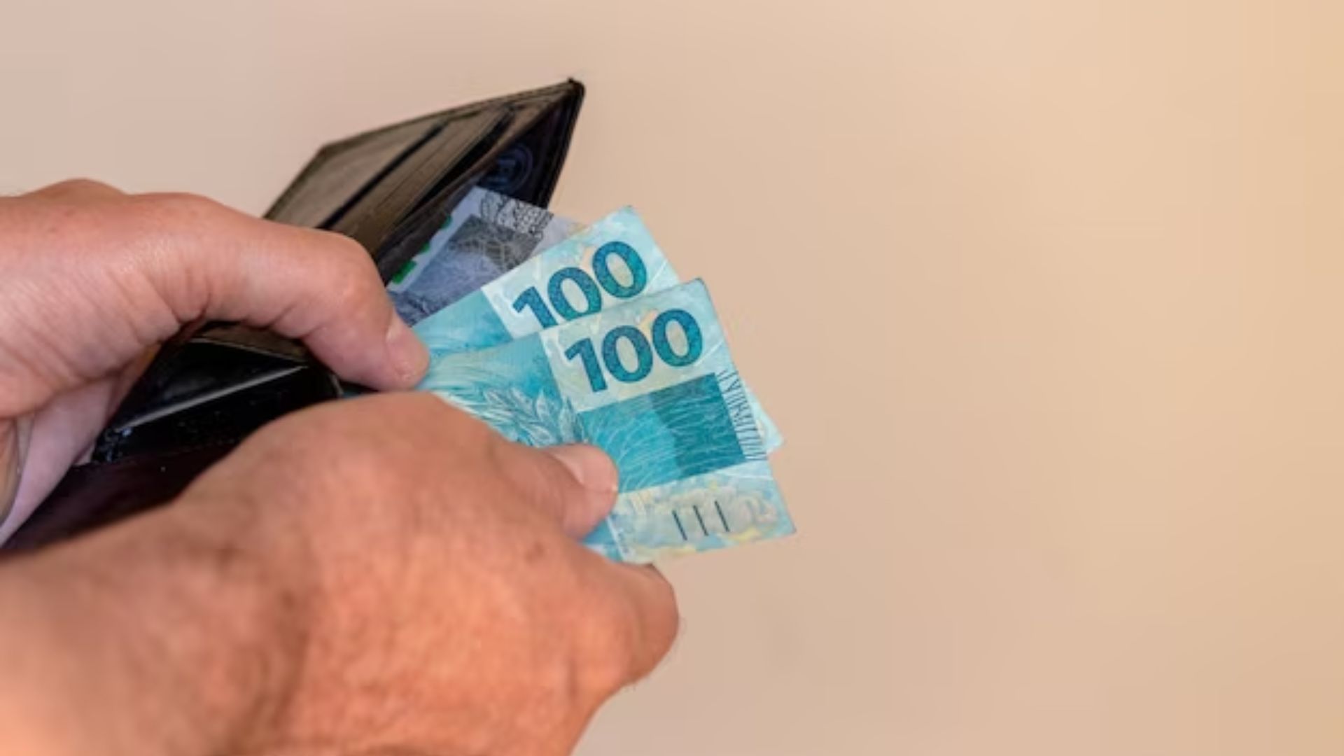 Homem tirando R$ 300 reais da carteira - Prazo para pagamento da 2ª parcela do 13º salário termina no dia 20 de dezembro