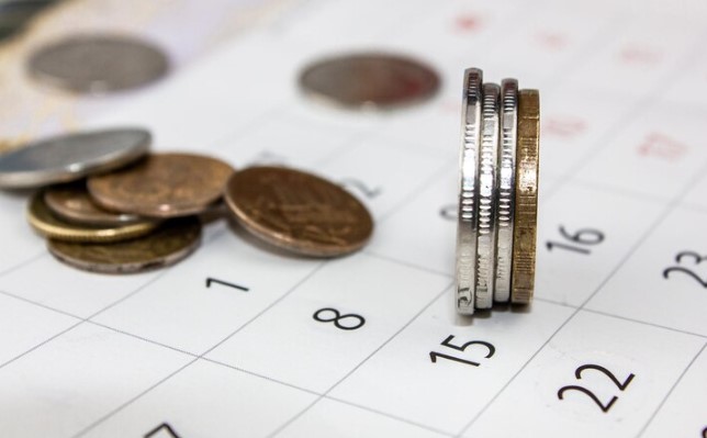 Agenda de Dividendos: foto de calendário e pilhas de moedas