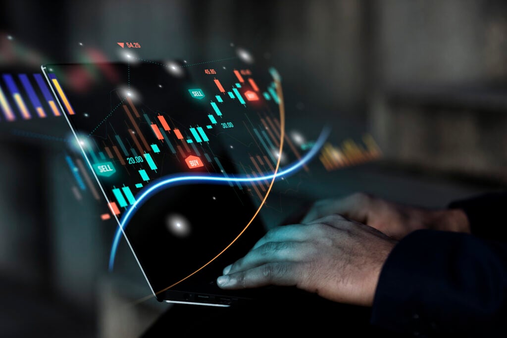 Investidor arrojado. Mãos de homem digitando em teclado de notebook, na tela aparecem candles ressaltados.