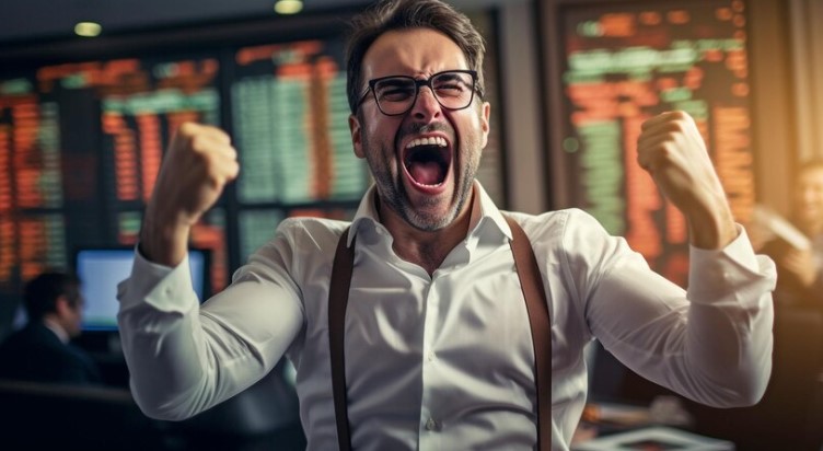 Foto de investidor arrojado: homem vibrando diante de quadro de ações