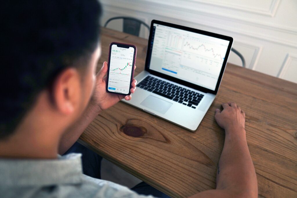 Investidor moderado perfil - Homem olhando gráficos de ativos no smatphone e no notebook.