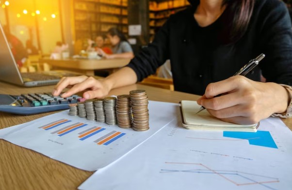 títulos incentivados: mulher fazendo cálculos frente a pilhas de moedas