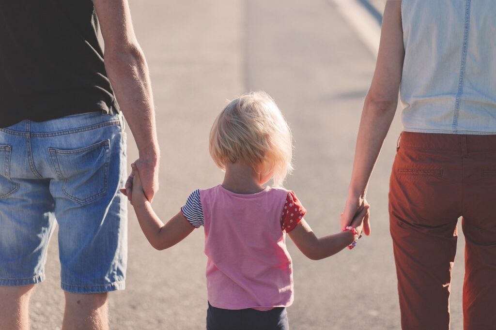 Declaração do Imposto de Renda. Família, pais de mãos dadas com a filha andando na rua.