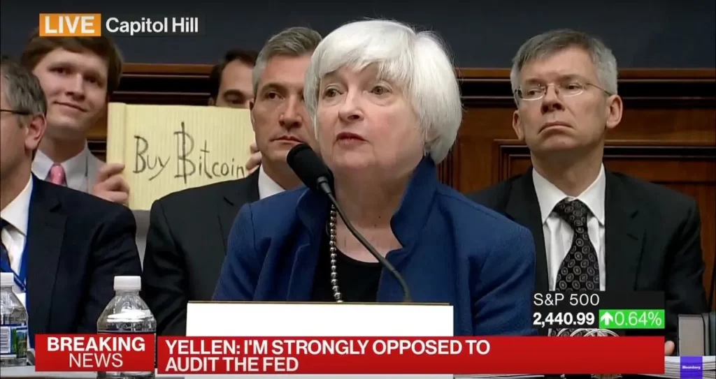 Bloco de notas com a mensagem "Buy Bitcoin" é exibido durante depoimento no Congresso norte-americano em 2017 atrás de Janet Yellen (Reprodução/Scarce.city)