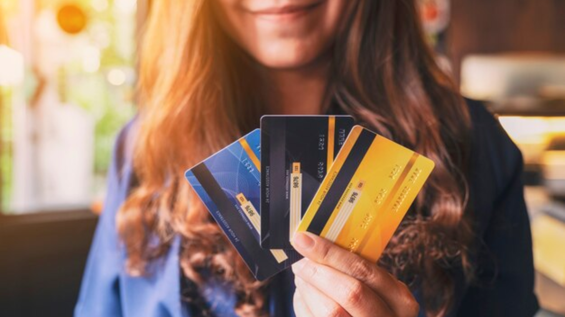 Mulher segurando vários tipos de cartões de crédito