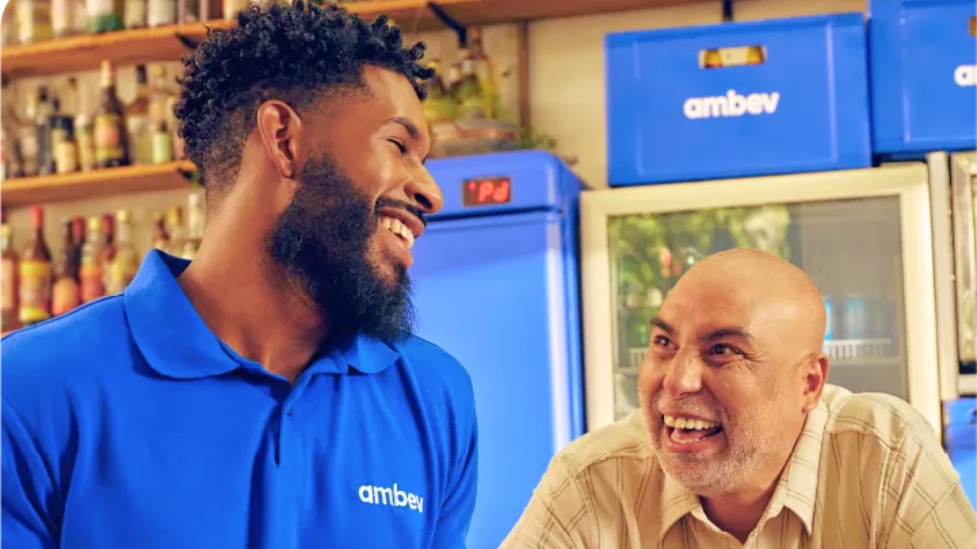 Dois homens conversando e dando risada com um deles usando uma camisa polo da Ambev