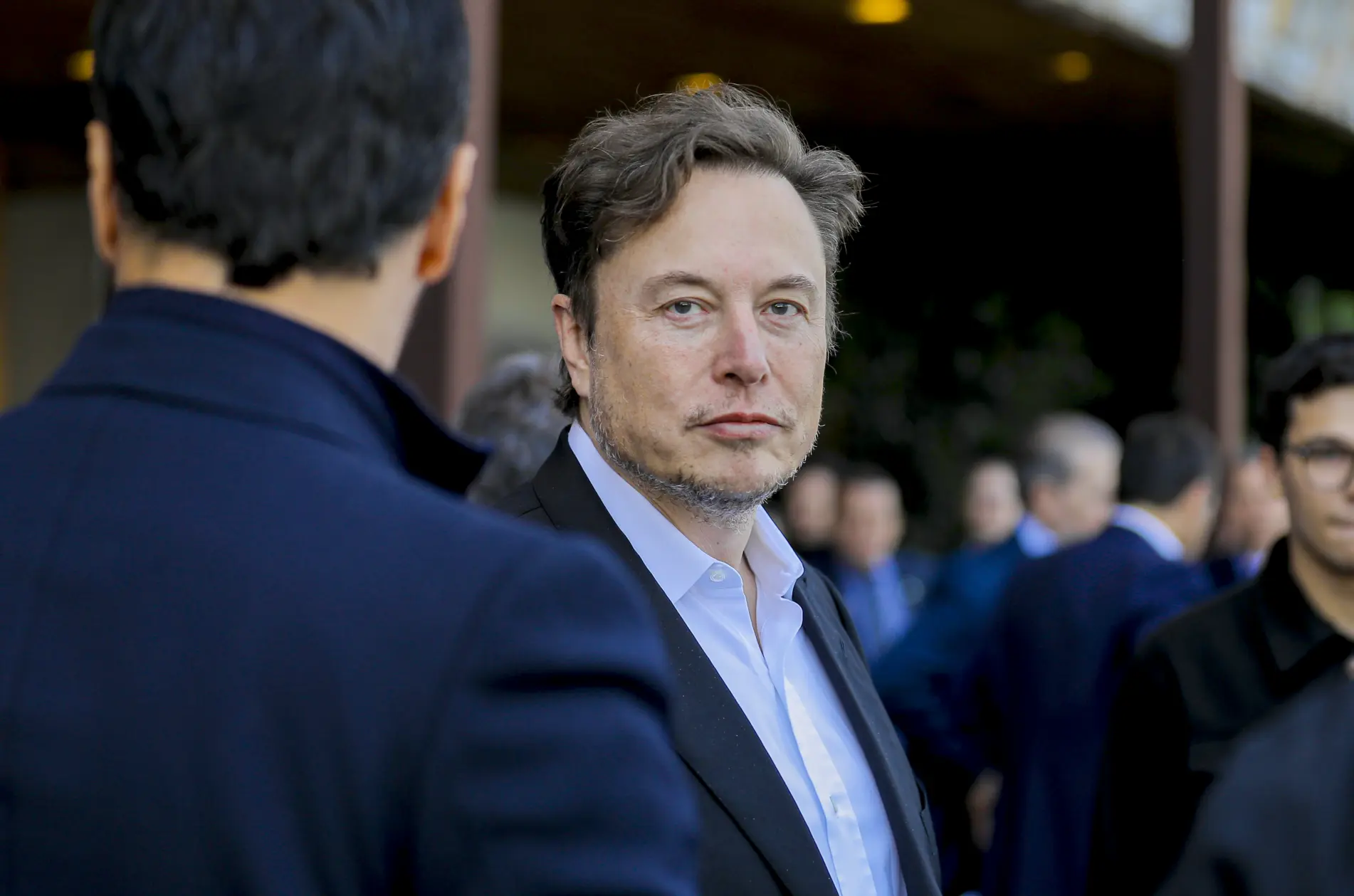 Foto mostra rosto de Elon Musk, em meio a outras pessoas