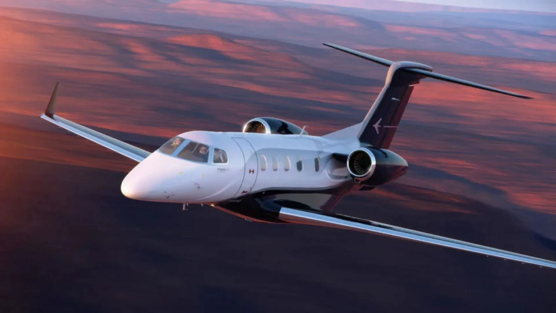 Jato executivo da Embraer em voo durante o pôr do sol