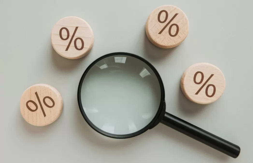 Super Quarta: Copom e Fomc decidem juros. Imagem de lupa e símbolos de porcentagem
