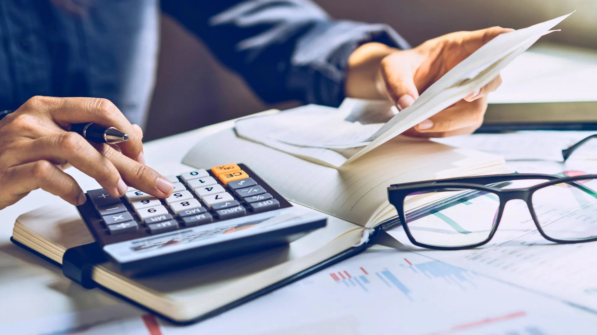 Pessoa com calculadora e documentos financeiros, representando a discussão sobre tributação de LCIs e LCAs pela Anbima