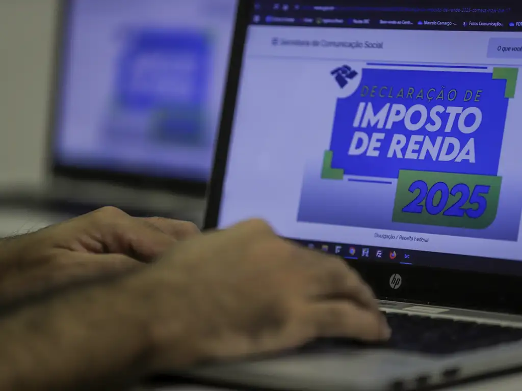 mãos mexem em um computador para observar a restituição do imposto de renda