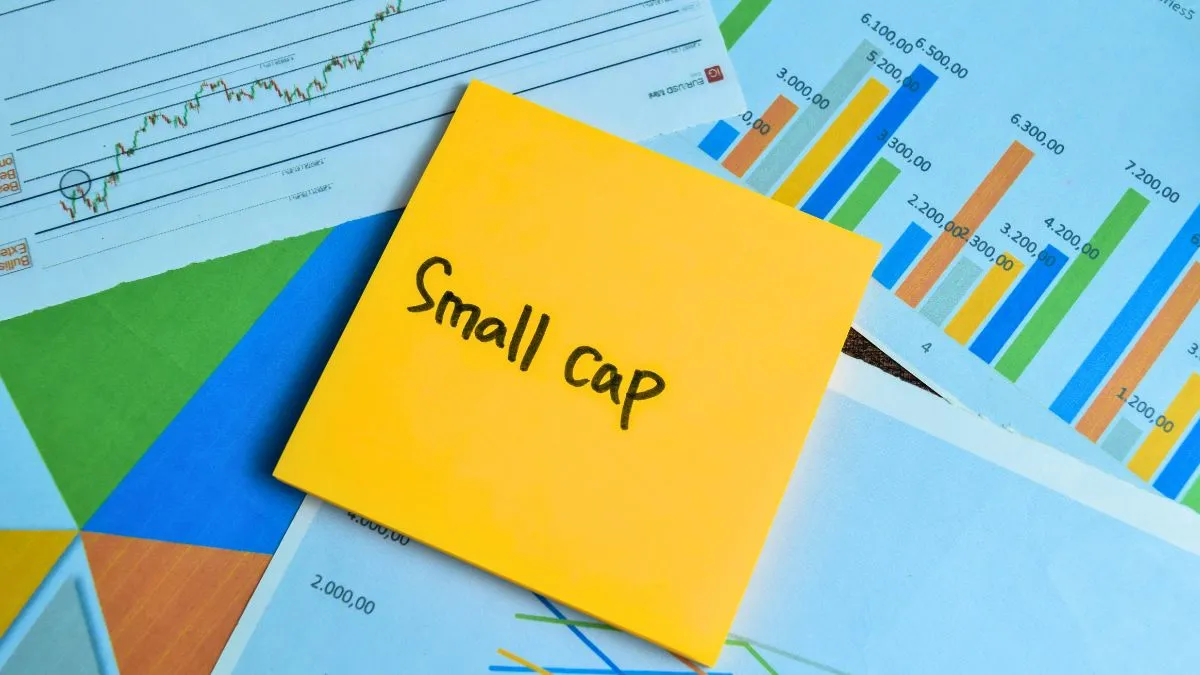 Post-it amarelo com "Small cap" escrito sobre documentos e gráficos, simbolizando investimentos.