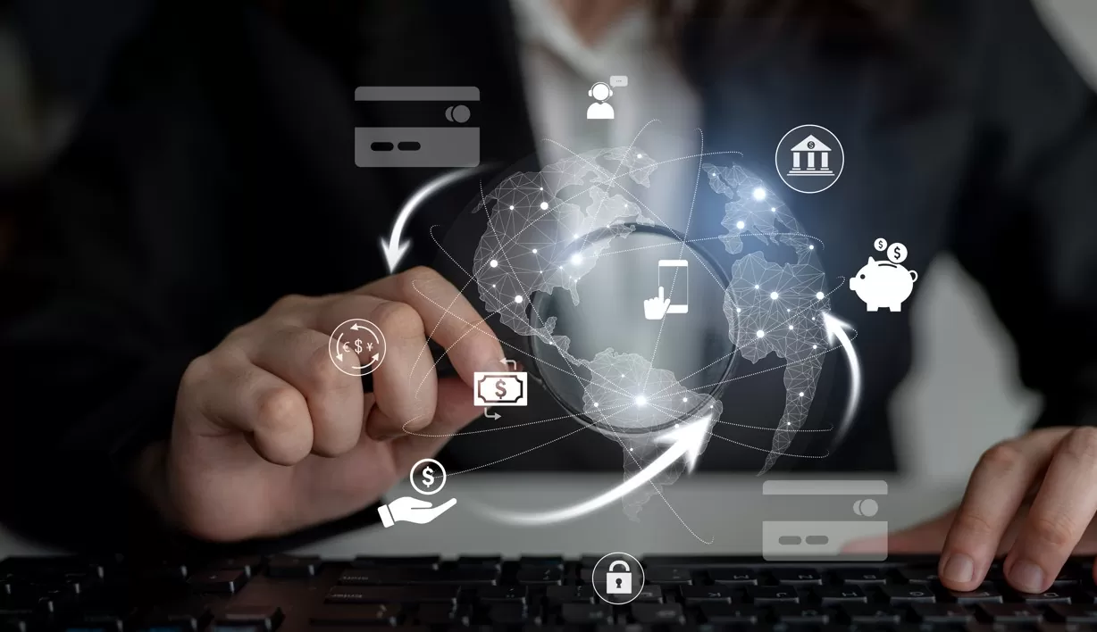 Quatro oportunidades para investir no exterior além dos EUA: imagem de homem analisando computador, com símbolos de investimento na tela